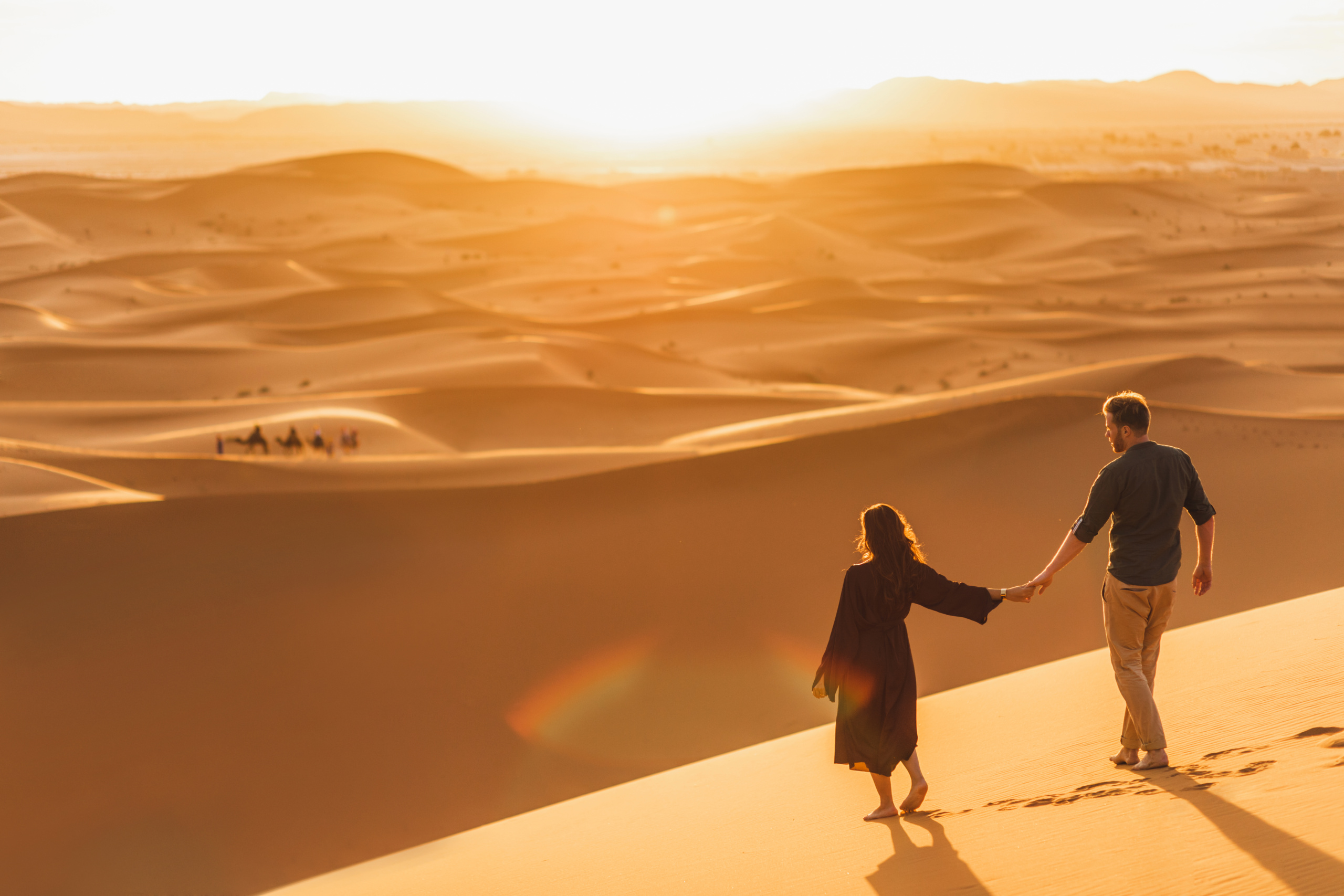 Couple,Walking,In,Sahara,Desert,At,Sunset.,View,From,Behind,